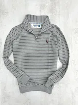 Buzo gris a rayas horizontales blancas y negras, con cuello alto y cierre metálico a la altura del pecho.