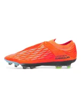 Championes de fútbol Under Armour Magnetico Elite 4 FG, color naranja vibrante con detalles en gris y verde neón. Presentan tecnología UA Clone en la parte superior para un ajuste personalizado, impresión 3D para mayor control y suela ligera con tacos mixtos para tracción multidireccional.