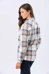 Campera de viyela a cuadros en tonos blanco, azul y tostado, forrada en corderito en su interior. Cuenta con cierre frontal de botones, bolsillos en el pecho con solapa y bolsillos laterales.
