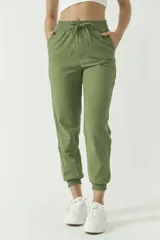 Pantalón de corte holgado confeccionado en mezcla de algodón y lino, color tostado. Presenta cintura elástica con cordón ajustable y puños elásticos en los tobillos.