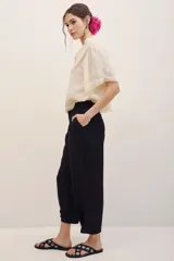 Pantalón negro de vestir de corte ancho y relajado, con cintura alta y detalles sutiles en el diseño.