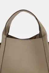 Bolso bandolera de formato city en color gris topo, con pespuntes decorativos, doble asa de mano, cremalleras laterales y cierre imantado.