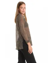 Camisa de tejido plisado y translúcido con hilos de lurex, de corte recto y manga larga. Presenta cuello con solapas, cierre frontal con botones y tajos laterales pronunciados en el bajo.