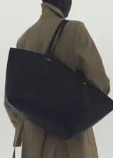 Bolso shopper negro de efecto piel, con dos asas de hombro, detalles metálicos, cierre de botón magnético y bolsillo interior con cremallera.
