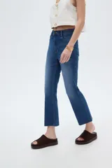Pantalón jean de corte recto y tiro alto, en color azul, con diseño clásico de cinco bolsillos y terminación desmechada en los tobillos.