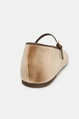 Zapato tipo bailarina de efecto terciopelo en color tostado, con tira fina ajustable con hebilla en el empeine y punta redonda.