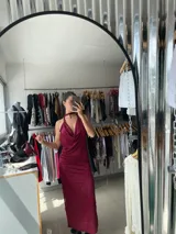 Vestido largo color borgoña con textura plisada, escote halter con cuello choker y espalda descubierta.