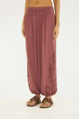 Pantalón aladín de silueta amplia y caída fluida, color rojo, con cintura elástica ancha con bordado y bajos de pierna fruncidos. Presenta detalles de bordado Richelieu en los laterales de las piernas.