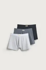 Pack de tres calzoncillos tipo bóxer de tejido elástico con acabado aterciopelado, en colores gris claro, gris oscuro y negro, con cintura elástica y etiqueta decorativa frontal.