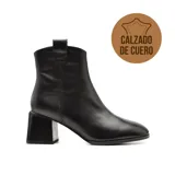 Bota de cuero negro con caña baja, punta fina y taco geométrico.