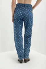 Jean de denim azul con calce recto y arte de dibujo láser con el monograma GG personalizado. Bordado a mano con lentejuelas y mostacillas doradas en cada rombo del arte láser. Botones en baño de oro con el grabado GNBR en bajo relieve y chapita GNBR también en baño de oro.