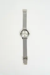 Reloj de pulsera analógico con malla metálica tipo milanesa y caja circular con bisel facetado.