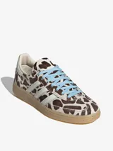 Championes Adidas modelo Handball Spezial W, con estampado animal print tipo vaca en tonos marrones y blancos, tiras laterales blancas, cordones celestes y suela de goma translúcida.
