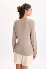 Sweater de punto color beige con hilos de lurex, escote en V y mangas largas con costuras en los hombros.