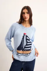 Sweater de punto color marfil con diseño de velero en la parte frontal, cuello con capucha y cordón rojo de ajuste.