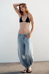 Jeans negro de tiro medio con corte balloon fit, diseño de cinco bolsillos y bajo acabado en puño con abertura y botón.