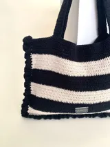 Bolso tipo tote tejido a crochet con hilo de algodón color marrón y crudo, con diseño a rayas horizontales y volados en los bordes.
