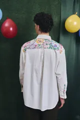 Camisa de corte oversize con mangas largas y puños abotonados. Presenta un diseño bicolor con cuerpo blanco y un canesú delantero con estampado floral multicolor.