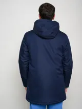 Parka larga de abrigo color azul marino, con capucha, cierre frontal, bolsillos con solapa y bolsillo superior con cierre. Presenta el logo de Umbro y el escudo del Club Nacional de Football.