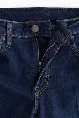 Jean de corte bootcut con cinco bolsillos, confeccionado en denim azul oscuro con leve stretch. Presenta cintura clásica, cierre con botón y raya planchada tanto en la parte frontal como trasera.
