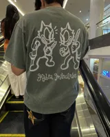 Remera marrón oversize de manga corta con estampado gráfico en la espalda de dos gatos de estilo retro con cuchillos y texto "Kahoa Industries".