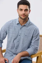 Camisa de manga larga confeccionada en mezcla de lino y algodón, con sutiles rayas celestes, cuello camisero clásico y cierre frontal de botones.