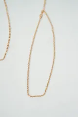 Set de tres collares dorados de diferentes diseños: uno con corazones y perlas, otro de eslabones y el último de cadena fina.