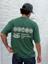 Remera oversize color verde bosque con estampado minimalista en blanco en el pecho: un globo terráqueo estilizado y el texto "STUDIO ARCHIVE".