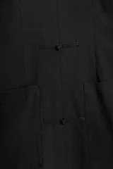 Vestido corto negro de cuello mao y escote en V, con mangas largas abanicadas y cierre de alamares en el frente. Cuenta con bolsillos frontales de plastrón y diseño de inspiración oriental.