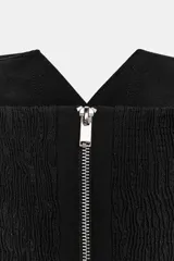 Top palabra de honor negro, corte estructurado con escote tipo solapa de blazer. Sin mangas y con cierre de cremallera oculta en costura.