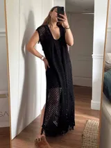 Chaleco largo de tejido calado tipo red, color negro, con hilo de algodón y lurex. Presenta escote profundo en V, tiras para atar, tajo trasero y flecos en el ruedo.