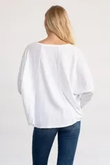 Remera de algodón de tejido liviano, con escote redondo amplio, mangas largas y silueta relajada. Presenta terminaciones desflecadas en el cuello y el ruedo, con un diseño de caída fluida.