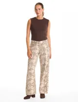 Jean de corte wide leg con estampado animal print de serpiente en tonos beige y gris. Presenta diseño clásico de cinco bolsillos, presillas para cinturón y cierre frontal con botón metálico.