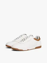 Zapatillas de corte bajo estilo retro baloncesto, confeccionadas en piel blanca con paneles de textura a contraste en color marrón y verde oliva en el talón. Presentan suela de goma dentada, cierre con cordones y logo de Tommy Hilfiger en el lateral y la lengüeta.