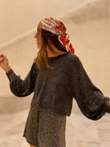 Buzo de tejido de punto con acabado brillante, confeccionado con hilado italiano. Presenta cuello redondo, mangas largas acampanadas y un corte holgado.