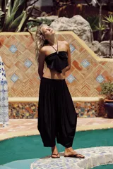 Pantalón bombacho negro confeccionado en tejido satinado, de tiro medio con cintura elástica y diseño con pliegues.