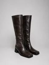 Botas de caña alta confeccionadas en 100 cuero color marrón oscuro con acabado texturizado efecto arrugado, punta cuadrada y taco bloque. Poseen cierre lateral interno.