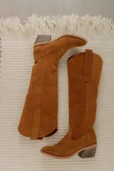 Botas de caña alta estilo western, confeccionadas en cuero negro, con taco cuadrado y detalle de tiradores laterales.