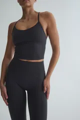 Top deportivo gris oscuro de tejido funcional con tecnología DryMove, escote amplio y breteles finos que se cruzan en la espalda.