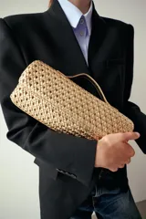 Bolso tipo sobre con diseño trenzado en color dorado. Cuenta con asa de mano fija, asa bandolera extraíble, bolsillo interior y cierre mediante solapa con imán.