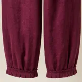 Pantalón de lino color bordó, con silueta relajada, cintura elastizada con lazo de ajuste, bolsillos laterales y detalle de pliegues con ruedo desflecado en los tobillos.