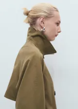 Abrigo tipo trench de diseño recto y oversize, color verde oliva. Presenta cierre de doble botonadura, cuello de solapa ancha, bolsillos laterales y mangas largas con puños abotonados. Incluye forro interior y cinturón desmontable.