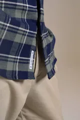 Camisa de manga larga confeccionada en tejido de franela con estampado de cuadros en tonos azul marino y verde. Presenta cuello abotonado, cierre frontal con botones y un bolsillo en el pecho con el logo bordado de la marca.