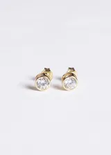 Aros tipo caravanas punto luz, con engaste circular y piedra de cristal central. Fabricados en plata 925 con baño de oro 18k.