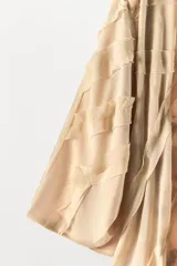 Kimono largo abierto de organza con mangas largas y aberturas laterales. Presenta un diseño con aplicaciones de tejido en relieve a tono y forro interior a contraste.