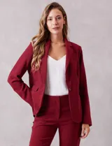 Blazer sastrero de corte entallado, color bordó, con cuello solapa, cierre frontal con un botón a tono y bolsillos laterales con solapa. Presenta hombreras ligeras para una silueta estructurada y forro interno.