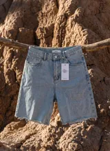 Bermuda de denim celeste claro, de corte relajado, tiro alto y con terminación desflecada en las piernas.