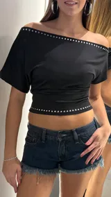 Top negro de manga corta con diseño de hombros descubiertos, adornado con una hilera de strass brillante en el escote y en el ruedo inferior.