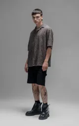 Camisa de manga corta con calce oversize y cuello abierto, confeccionada en algodón con diseño de bordado tipo broderie y efecto de desgaste en el color.