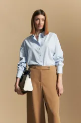 Pantalón ancho color tostado, de silueta fluida y cintura elastizada. Presenta una pretina ancha con botones metalizados irregulares.